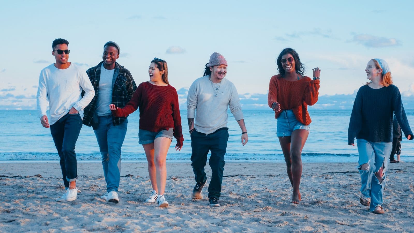 A group of friends walking and laughing together on a beach